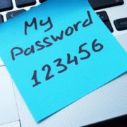 Sticky note with text "My Password 123456" laying on a laptop keyboard