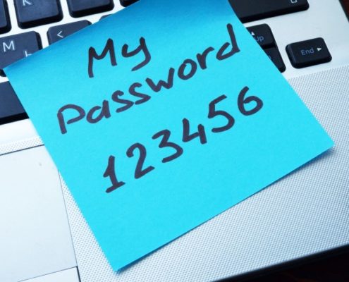 Sticky note with text "My Password 123456" laying on a laptop keyboard